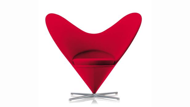 Ein roter Sessel in ungewöhnlicher Form steht auf einem silbernen Fuß.