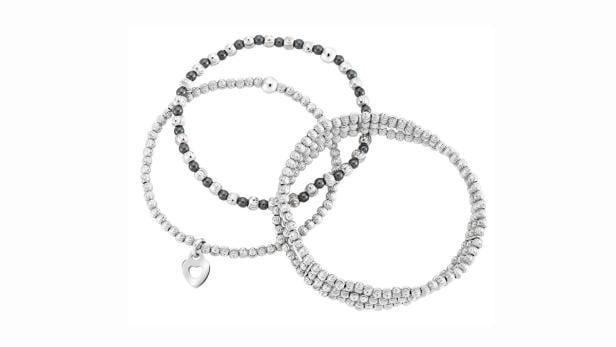 Drei silberfarbene Armbänder mit Perlen, eines davon mit einem Herzanhänger.