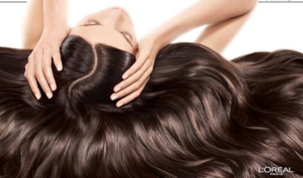 Eine Frau liegt mit ihren langen, braunen Haaren, die von L'Oréal Paris beworben werden.