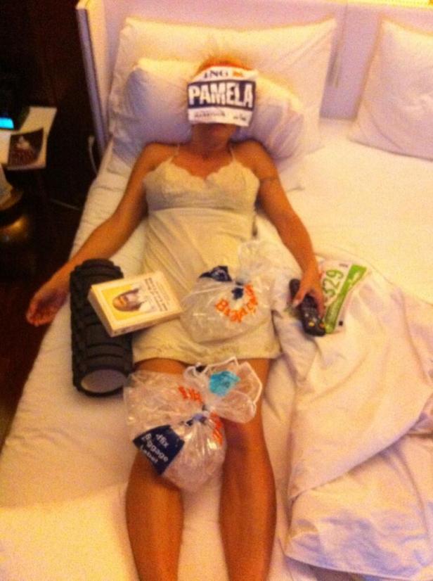 Eine Frau liegt mit einem „Pamela“-Namensschild auf den Augen und Eisbeuteln im Bett.