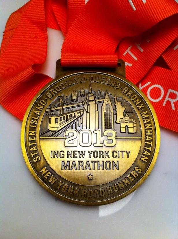 Eine Medaille des New York City Marathon 2013 mit orangefarbenem Band.