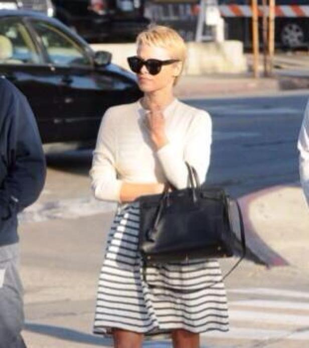 Pamela Anderson mit Sonnenbrille und Handtasche auf der Straße.