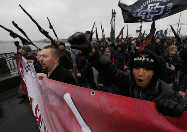 Eine Menschenmenge demonstriert mit schwarzen Flaggen und einem roten Banner.