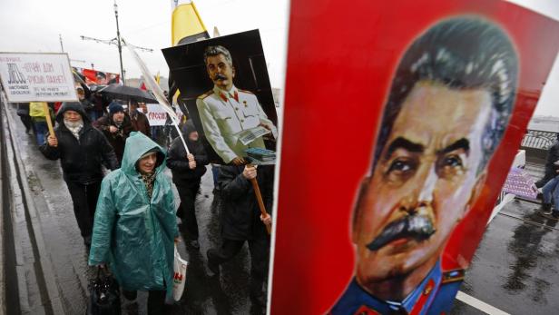 Menschen demonstrieren mit Porträts von Stalin und Schildern in russischer Sprache.