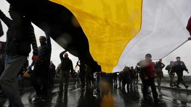 Menschen tragen eine große russische Flagge bei einer Demonstration.