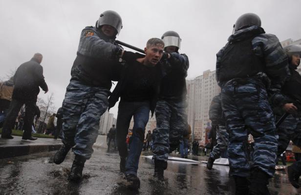 Polizisten in Kampfmontur führen einen jungen Mann ab.