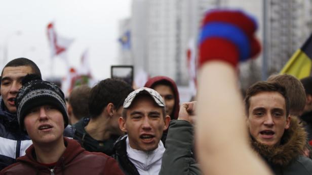 Eine Menschenmenge demonstriert mit erhobenen Fäusten und weiß-rot-weißen Flaggen.