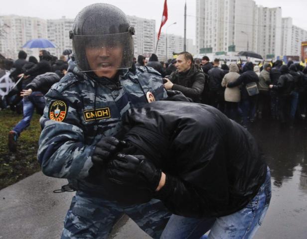 Ein Polizist in Schutzkleidung führt eine Festnahme bei einer Demonstration durch.