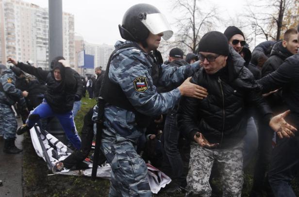 Ein Polizist in Uniform führt eine Person bei einer Demonstration ab.