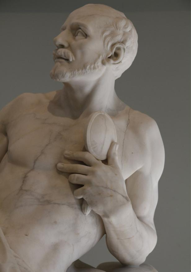 Eine Marmorstatue von Narziss, der sein Spiegelbild betrachtet.