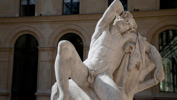 Eine Marmorstatue, die einen liegenden, muskulösen Mann darstellt.