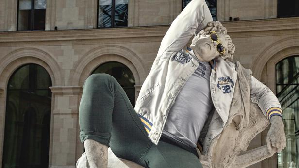 Eine Statue trägt eine Jacke und eine Sonnenbrille vor einem Gebäude.