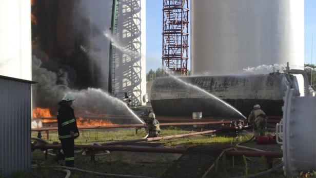 Feuerwehrleute bekämpfen einen Brand in einem Tanklager mit Wasserwerfern.