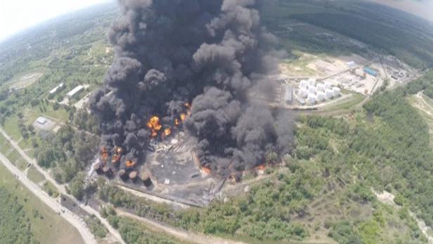Ein Ölbrand verursacht eine riesige Rauchwolke über einem Industriegebiet.