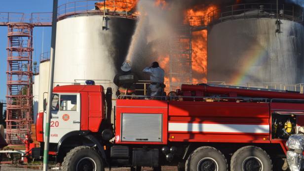 Feuerwehrleute bekämpfen einen Brand in einem Tanklager mit einem Wasserwerfer.
