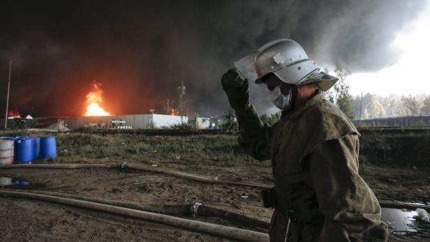 Ein Feuerwehrmann mit Helm und Maske vor einem Brandherd.