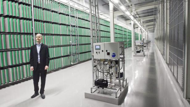 Ein Mann in einem Anzug steht in einer Halle mit Luftfiltern und Reinigungsanlagen.