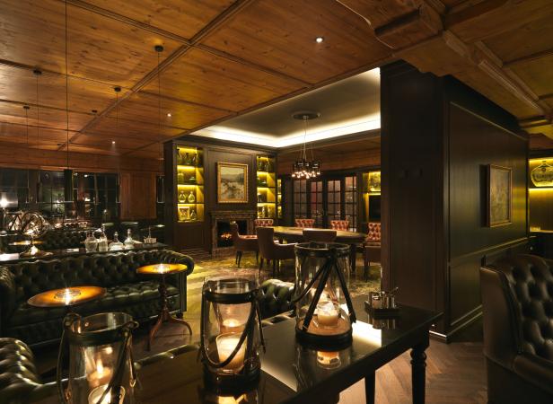 Ein luxuriöser Aufenthaltsraum mit Holzdecke, Ledersofas und Kamin.