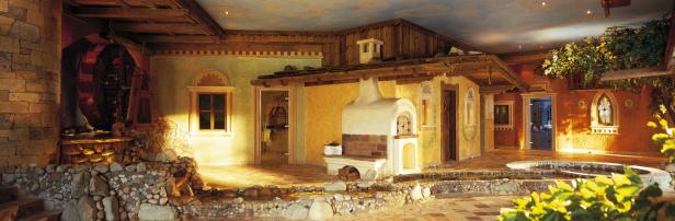 Ein Innenraum mit einem kleinen Bachlauf, einem Wasserrad und einem Ofen.