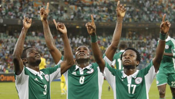 Drei nigerianische Fußballspieler jubeln mit erhobenen Zeigefingern.