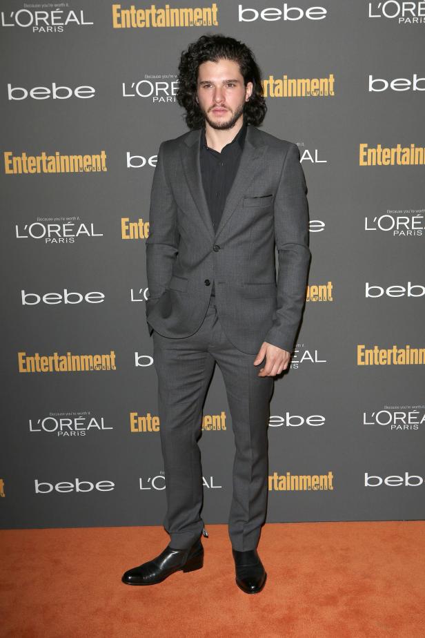 Kit Harington posiert auf einem Event auf einem orangefarbenen Teppich.