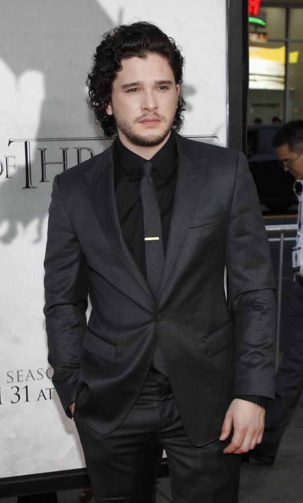 Kit Harington in einem dunklen Anzug auf einem roten Teppich.