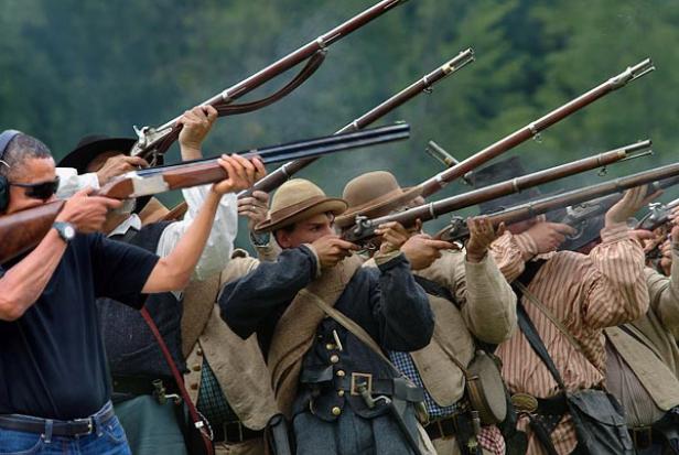 Eine Gruppe von Männern in historischen Kostümen feuert Gewehre ab.