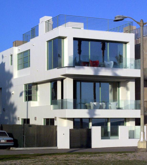 Ein modernes, dreistöckiges, weißes Haus mit großen Fenstern und Balkonen.