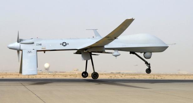 Eine graue Militärdrohne landet auf einer Landebahn.