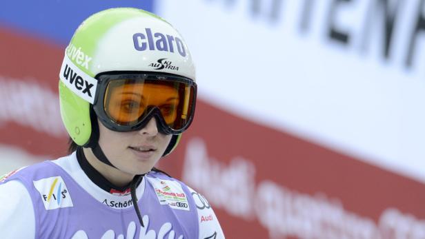 Eine Skirennläuferin mit Helm und Skibrille vor einem verschwommenen Hintergrund.