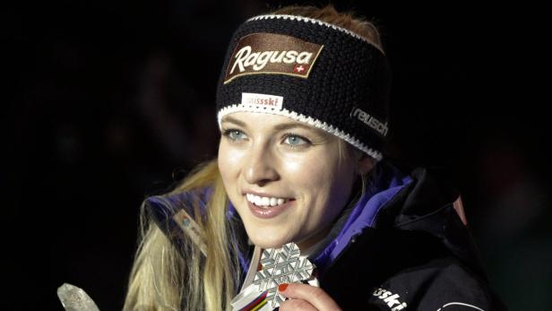 Eine blonde Frau mit Stirnband und einer Silbermedaille um den Hals lächelt.