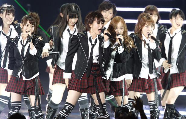 Eine japanische Girlgroup tritt in Schuluniformen auf einer Bühne auf.