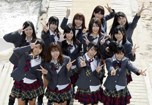 Eine Gruppe japanischer Schülerinnen in Uniform posiert für ein Foto am Strand.
