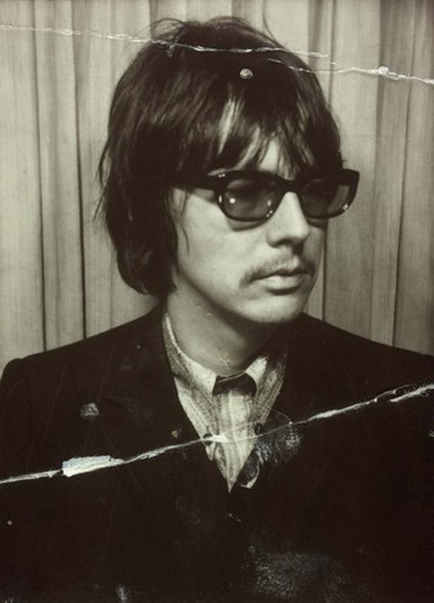 Ein Mann mit Brille und Schnurrbart in einem beschädigten Schwarzweißfoto.