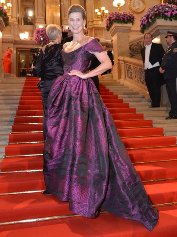 Eine Frau in einem violetten Ballkleid auf einer roten Treppe.