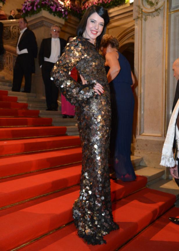 Eine Frau in einem Paillettenkleid posiert auf einer roten Treppe.