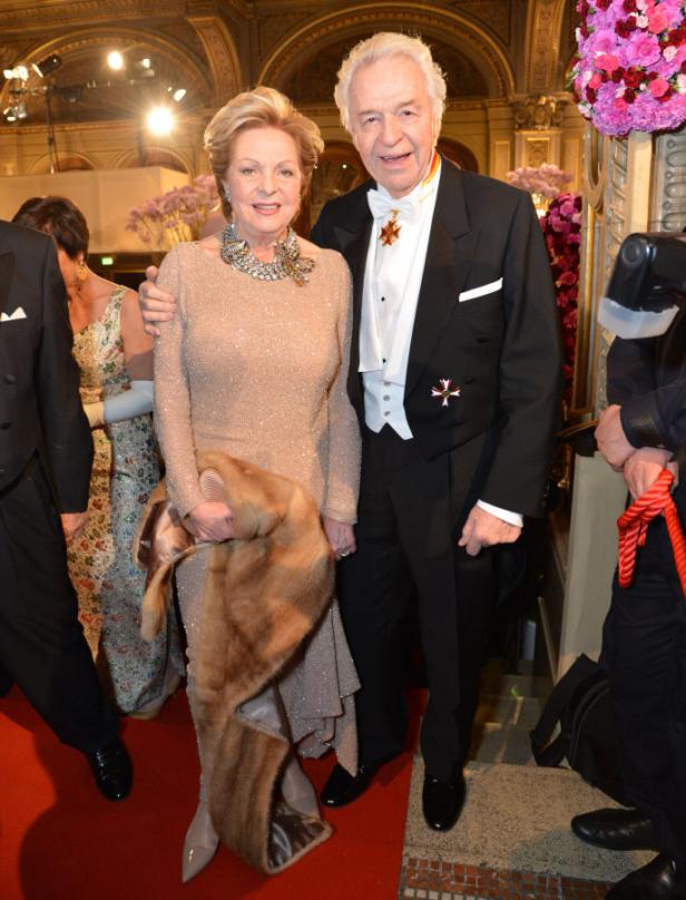 Ein älteres Paar posiert elegant in Abendgarderobe auf einem roten Teppich.