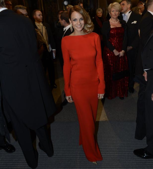 Eine Frau in einem roten Kleid posiert auf einem Event.