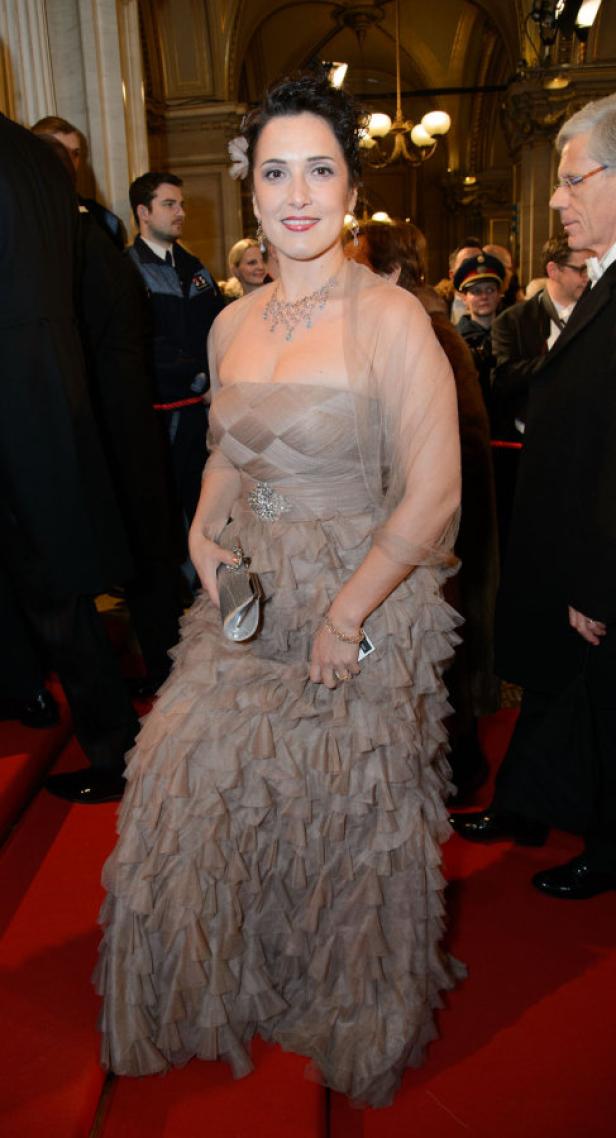 Eine Frau in einem eleganten, rüschenbesetzten Kleid auf einem roten Teppich.