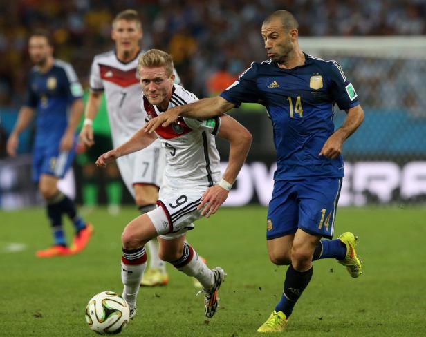Ein deutscher und ein argentinischer Fußballspieler kämpfen um den Ball.