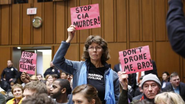 Eine Frau demonstriert mit anderen gegen Drohnenangriffe und CIA-Operationen.