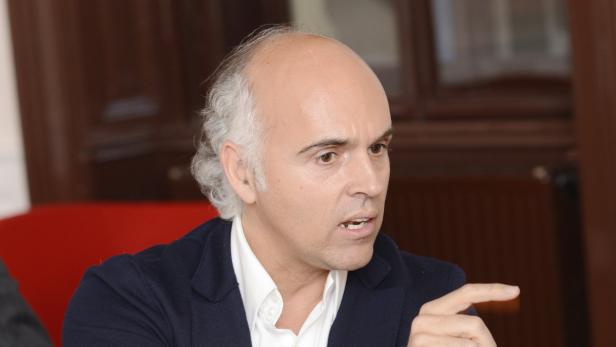 Ein Mann mit grauem Haar gestikuliert mit dem Finger.