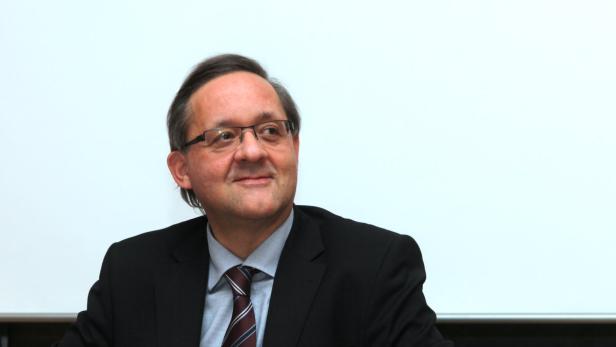 Ein Mann mit Brille, Anzug und Krawatte blickt nach rechts.