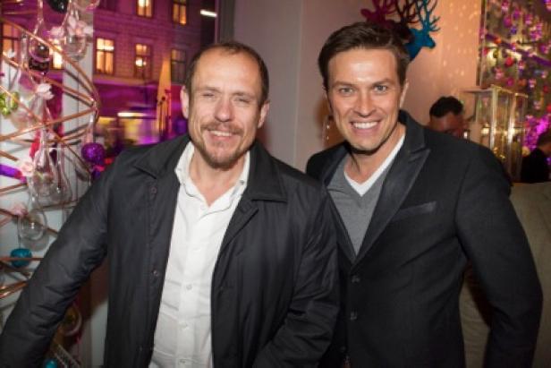Zwei Männer posieren lächelnd für ein Foto auf einer Party.