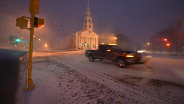 Ein Pick-up fährt bei Schneefall an einer Kirche vorbei.