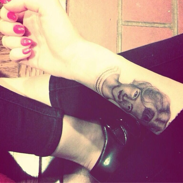 Auf dem Unterarm einer Person befindet sich ein Porträt-Tattoo.