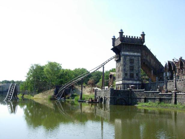 Eine Achterbahn schlängelt sich um einen Turm und über einen See.