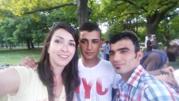 Eine Frau und zwei Männer machen ein Selfie im Park.