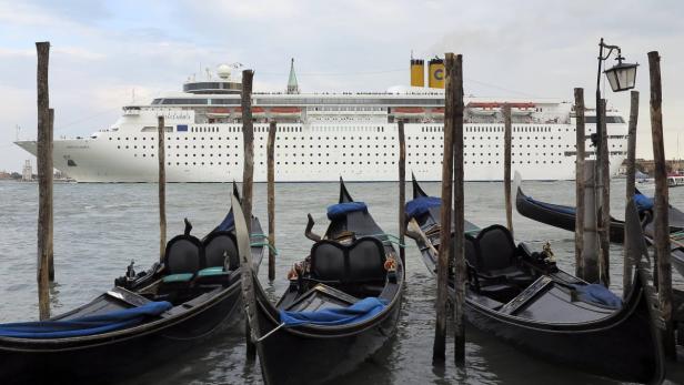 Gondeln liegen vor einem großen Kreuzfahrtschiff in Venedig.