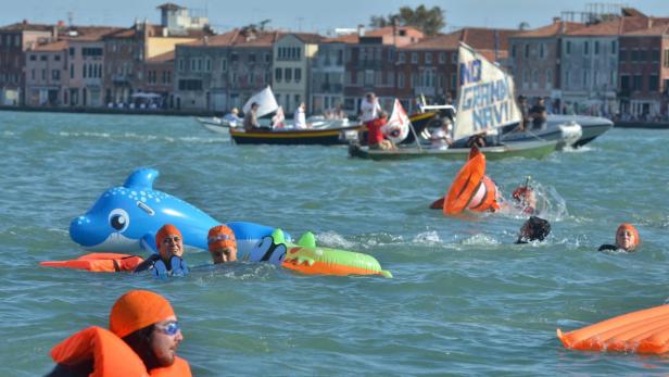 Schwimmer mit Schwimmhilfen nehmen an einer Veranstaltung in einem Kanal in Venedig teil.